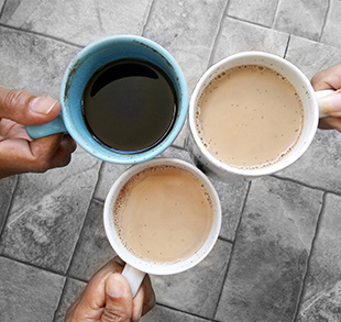 Adults holding three full cups of coffee