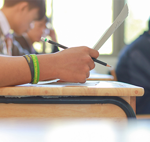 Student holding papers on his desk