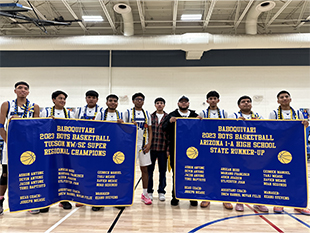 Boys basketball team holding up big banners in the gym