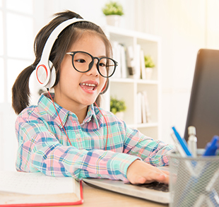 Little girl with headphones working on a laptop